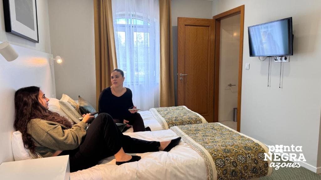 Two women watching TV on single beds